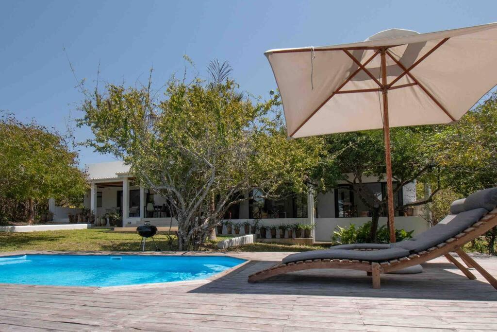 a chair and an umbrella next to a pool at VillaFour@Tsai-Tsai in Vilanculos