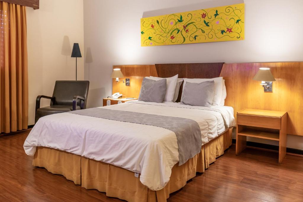a hotel room with a large bed and a chair at Dexter Hotel - Volta Redonda in Volta Redonda