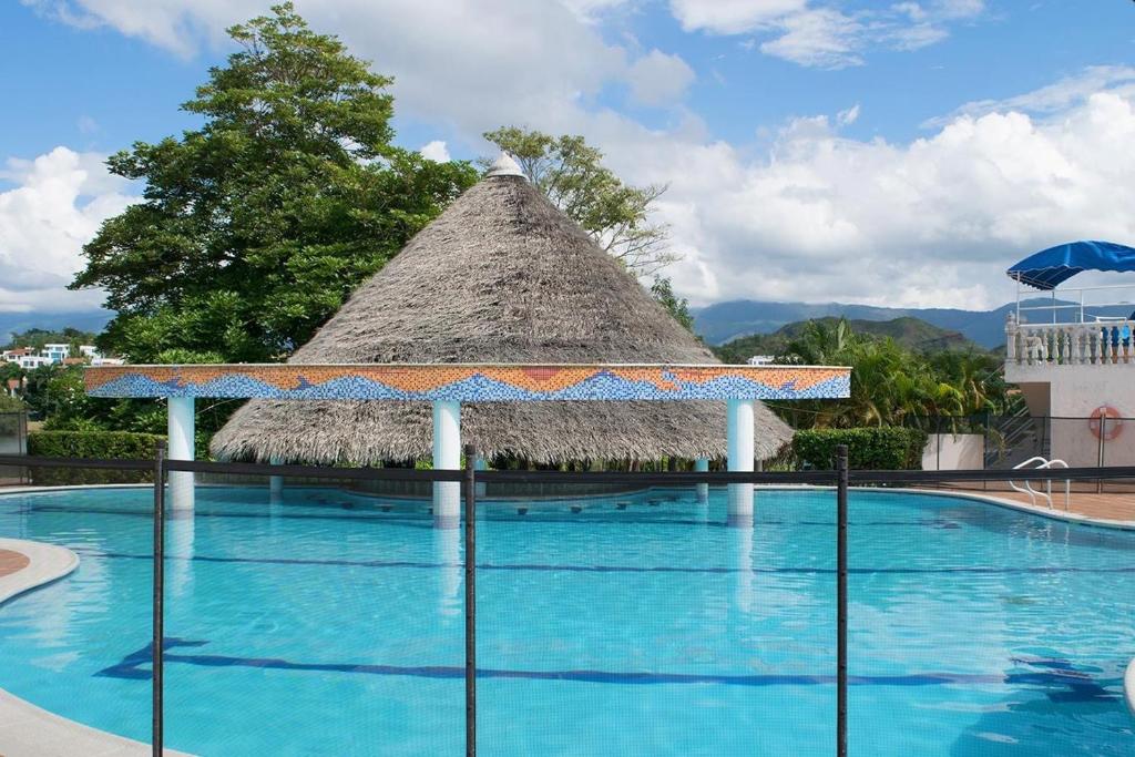 une grande piscine avec toit de chaume dans l'établissement Casa campestre Hacienda la estancia, en Melgar con piscina privada, à Melgar