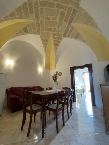 a dining room with a table and a couch at Casetta Parini in Porto Cesareo