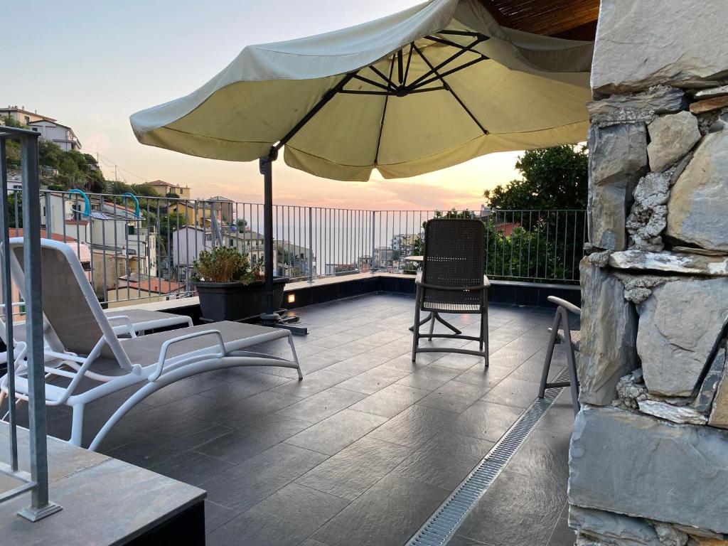 un patio con 2 sillas y una sombrilla en el balcón en Locanda Ca Da Iride, en Riomaggiore