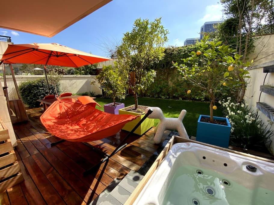 un patio trasero con bañera de hidromasaje y sombrilla en Appartement avec Jacuzzi - Climatisation - Parking en Burdeos