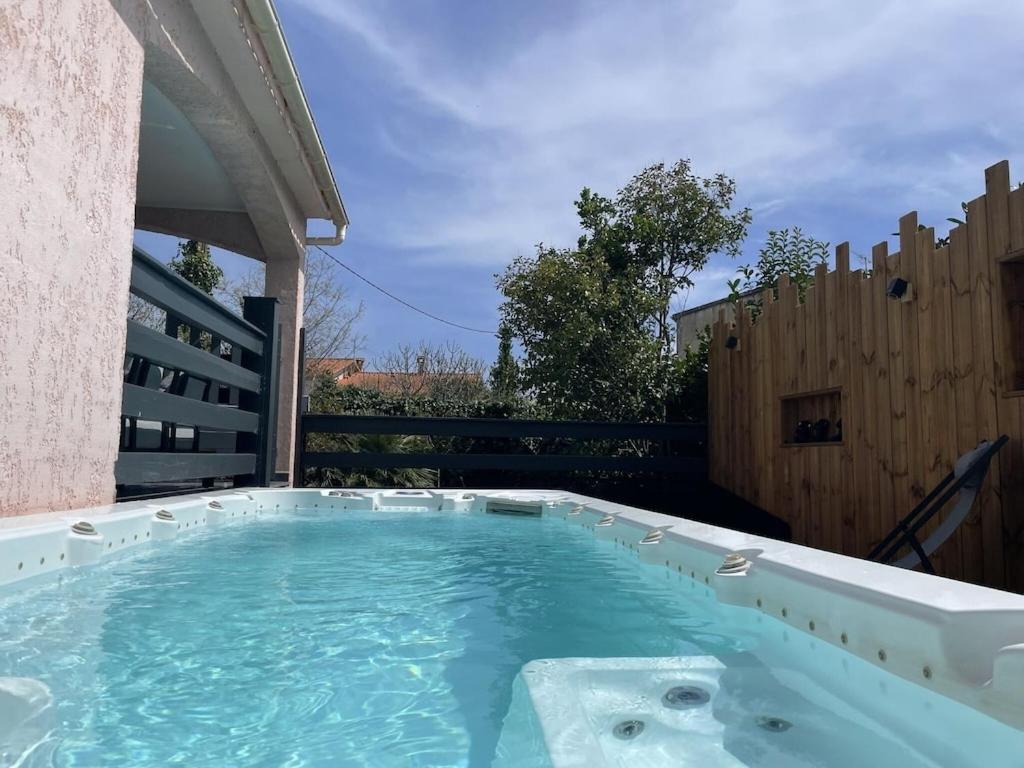 einen Whirlpool im Hinterhof mit einem Holzzaun in der Unterkunft Villa avec piscine entièrement rénovée à 5min de la plage de pinia in Ghisonaccia