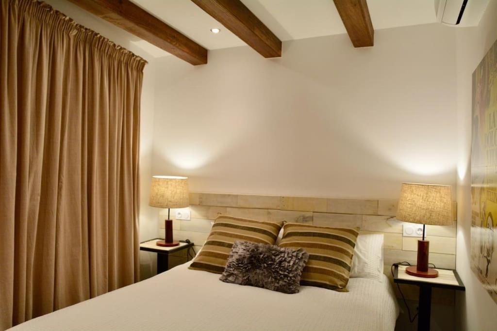 a bedroom with a white bed with two lamps at Can Senio 2 in Tossa de Mar