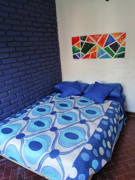 a bedroom with a bed with blue pillows and a brick wall at La Casita de Mogotes in Mar del Plata