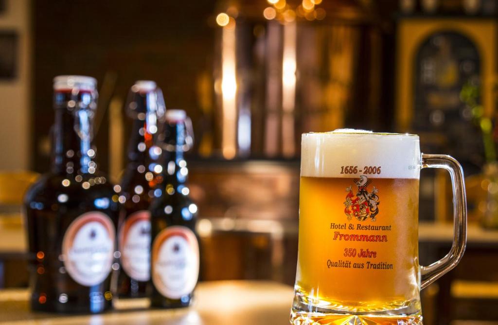 a glass of beer sitting on a table with beer bottles at Frommanns Landhotel in Buchholz in der Nordheide