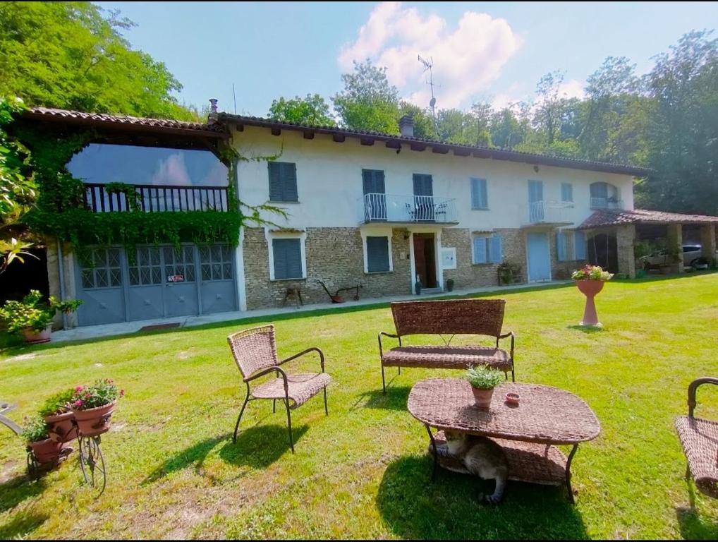a yard with chairs and a table and a house at Il mestiere di vivere -casa vacanze- in Santo Stefano Belbo