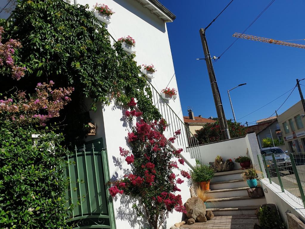 une maison blanche avec un portail vert et des fleurs dans l'établissement Appartement duplexe de 1 à 4 chambres privées dans maison, à Le Teil