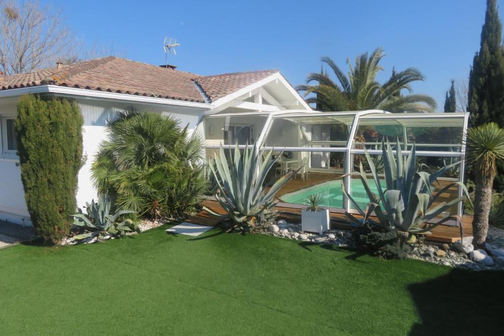 a white house with a yard with palm trees at Villa Baïne 8p seignosse in Seignosse