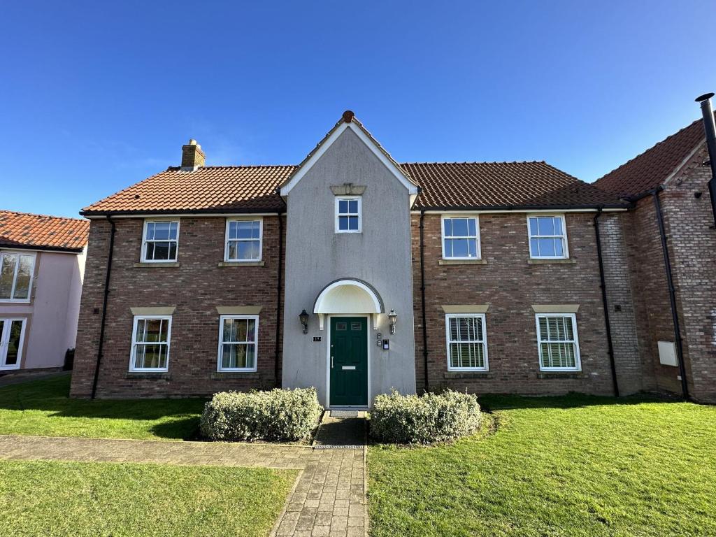 une grande maison en briques avec une porte verte dans l'établissement Meadowside Apartment, à Filey