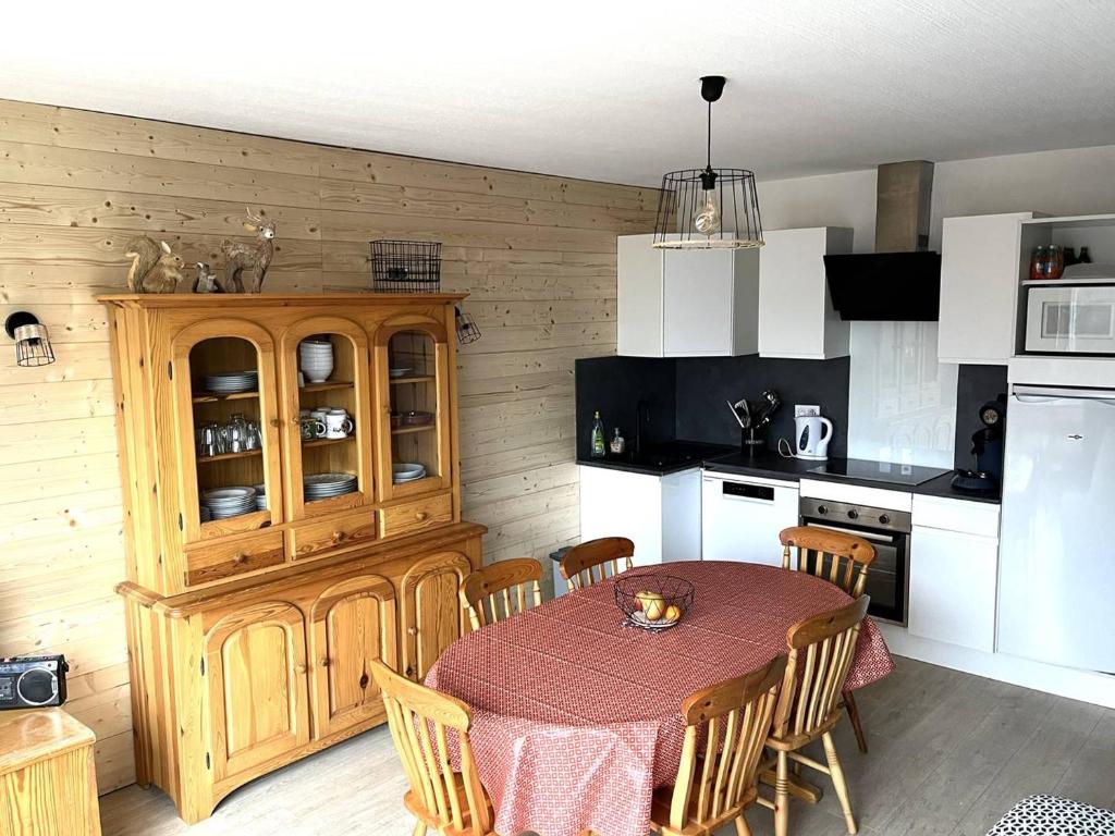 eine Küche mit einem Tisch mit Stühlen und einem Holzschrank in der Unterkunft Appartement Bolquère-Pyrénées 2000, 3 pièces, 8 personnes - FR-1-592-57 in Font Romeu Odeillo Via
