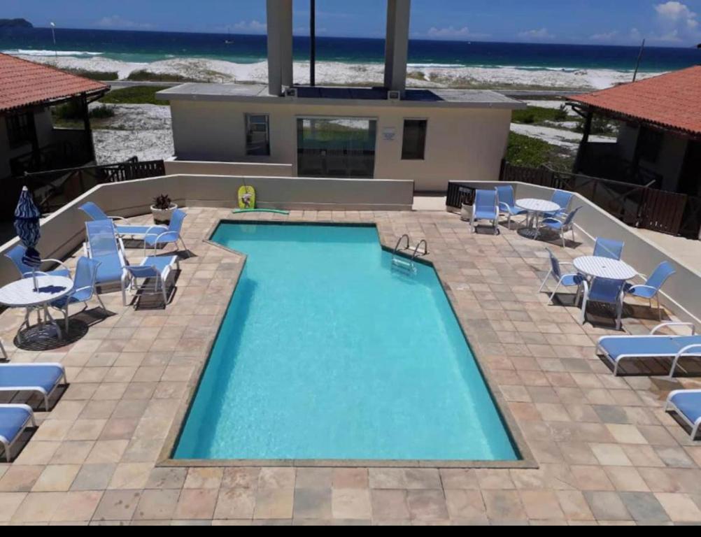einen Pool mit Stühlen und Tischen und ein Haus in der Unterkunft Casa familiar pé na areia in Cabo Frio