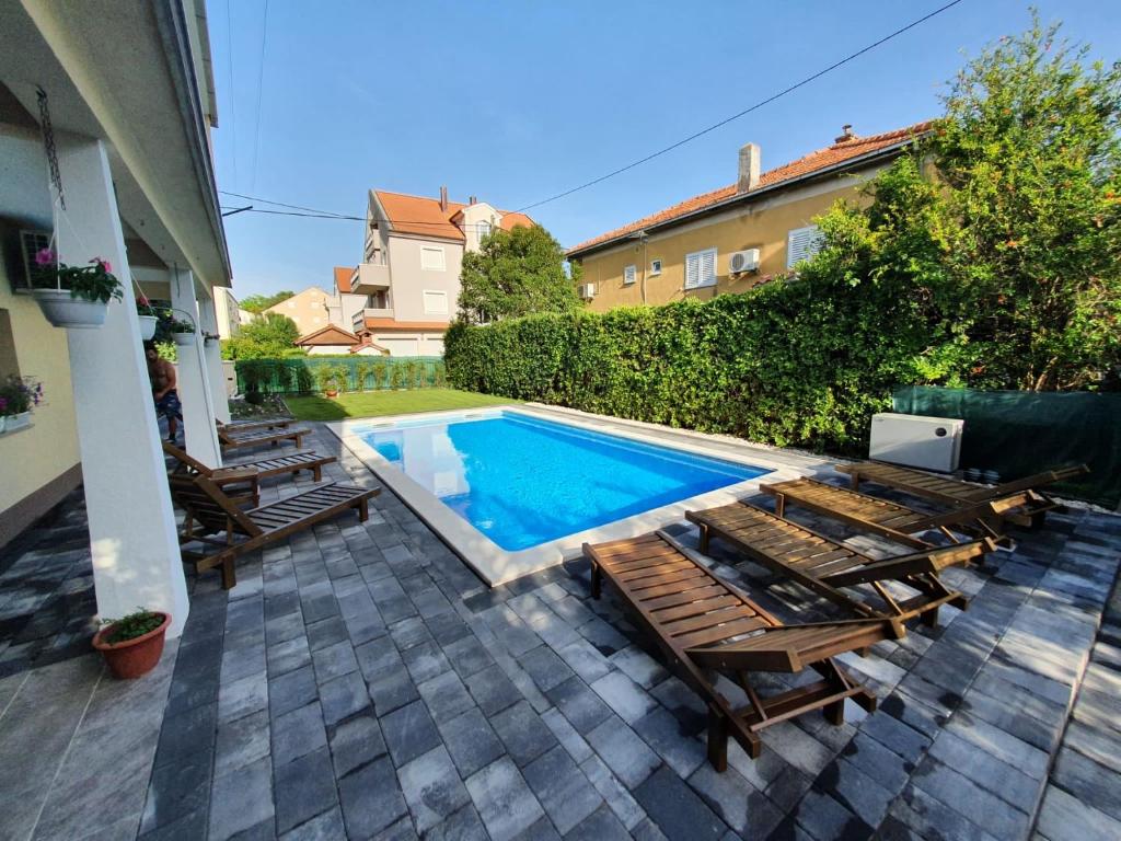 a swimming pool with chaise lounge chairs next to a house at Villa Isabella with private heated pool in Kaštela