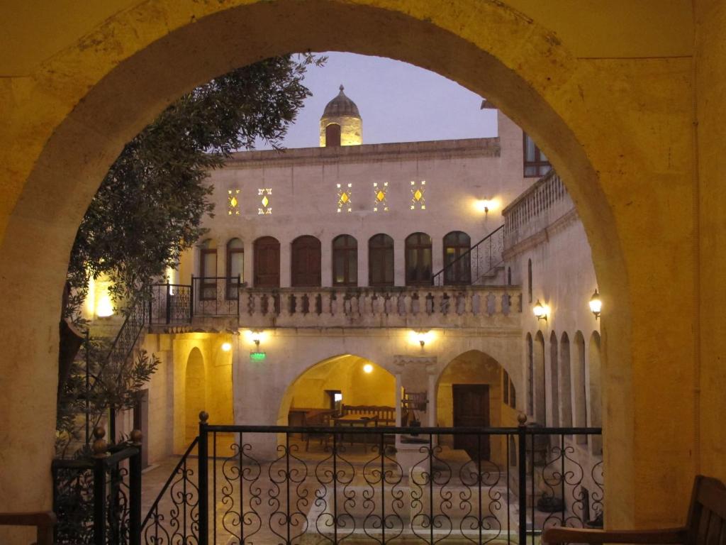 un arco que conduce a un edificio con una torre de reloj en Elci Konagi Butik Hotel, en Sanlıurfa