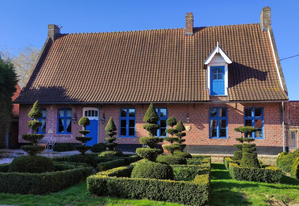 une maison en briques rouges avec un toit et un jardin dans l'établissement Manoir du Kasteelveld, à Cassel