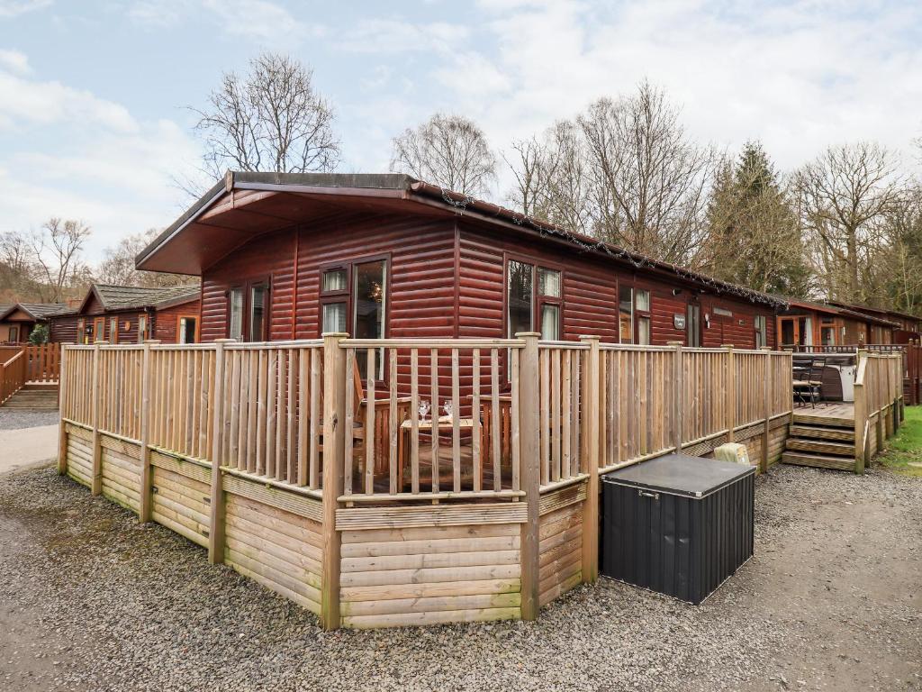 a wooden cabin with a fence in front of it at Brightwater Lodge in Windermere