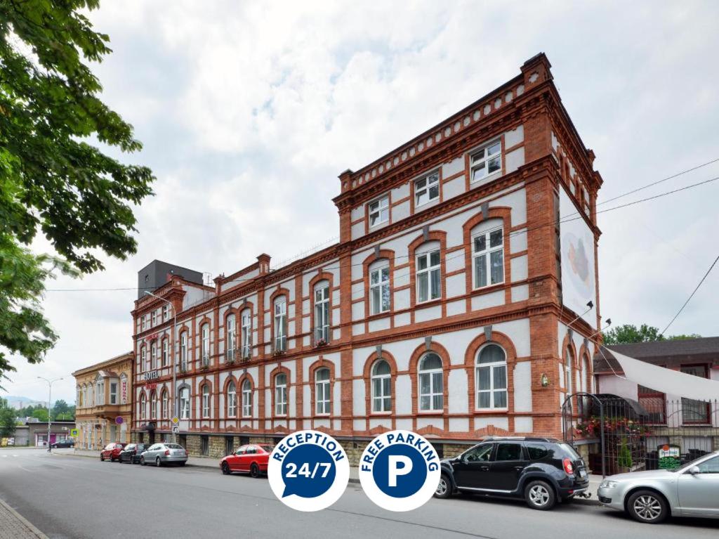 a large brick building with cars parked in front of it at Hotel RICHTR in Frýdek-Místek