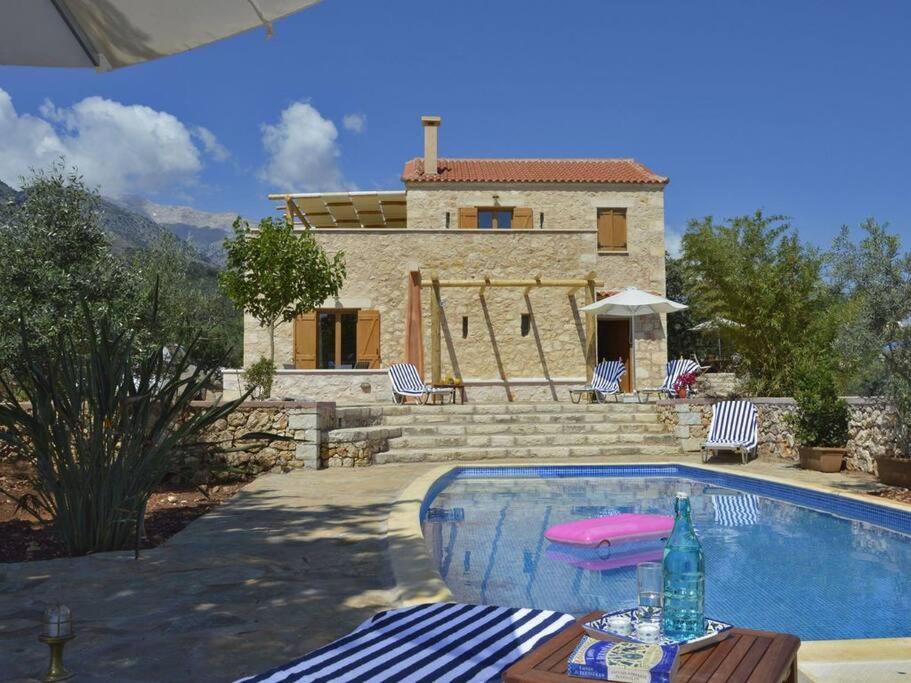 Casa con piscina y mesa con botella en Villa Ariadne en Melidhónion