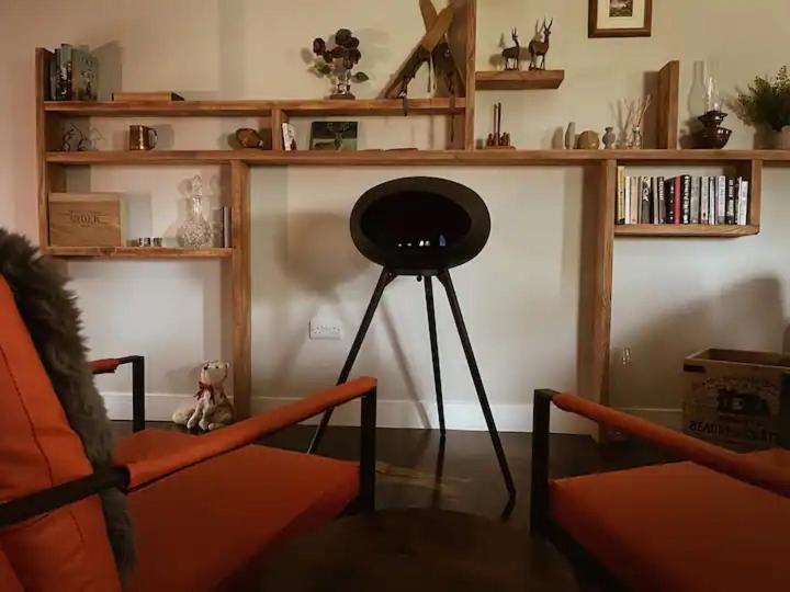 a living room with a chair and a table and shelves at The Bothy in Stirling