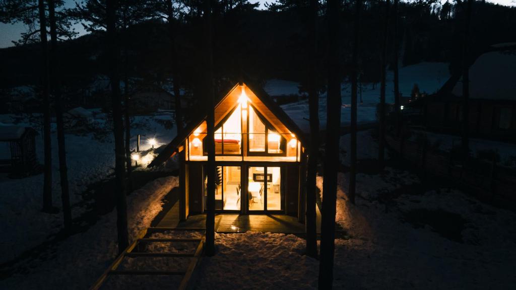 una pequeña cabaña en la nieve por la noche en HIŠA ZIMAZAKON BLOKE, en Nova Vas