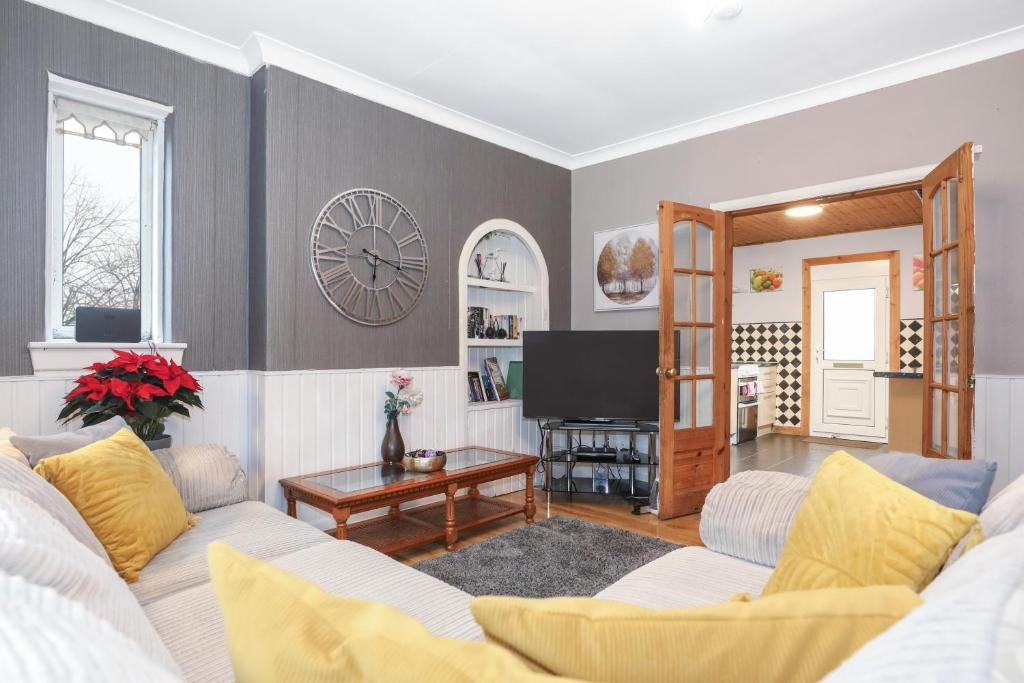 a living room with a couch and a clock on the wall at Beautiful Rooms in Edinburgh Cottage Guest House - Free Parking in Edinburgh