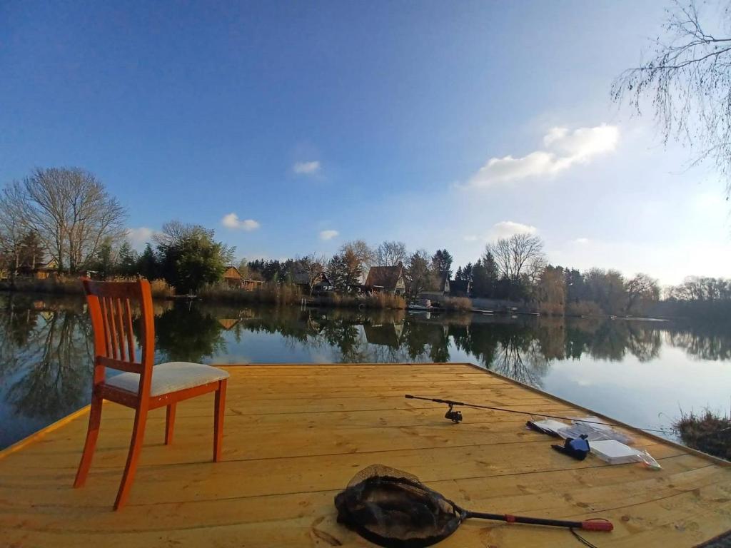 a chair sitting on a dock next to a lake at Bónom-zugi Pihenőház in Gyomaendrőd