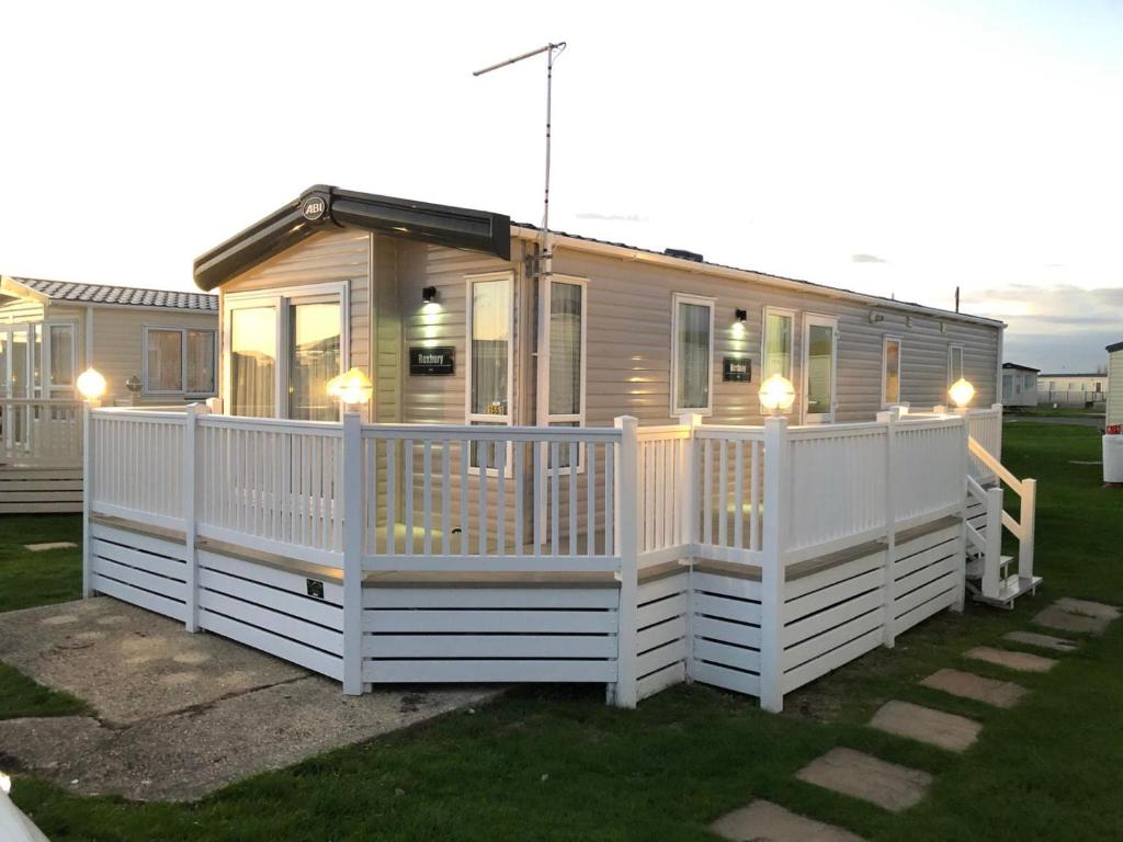 a tiny house with a white fence on a yard at The Sherbourne in Selsey