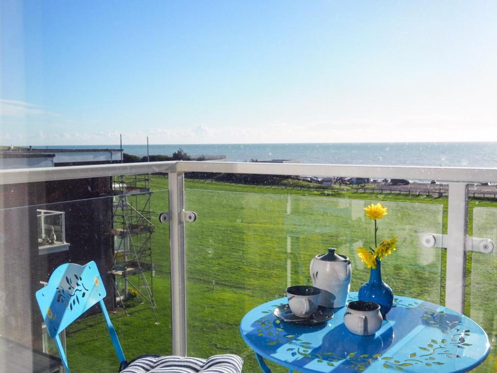 a table on a balcony with a view of the ocean at Galley Hill Aspect in Bexhill