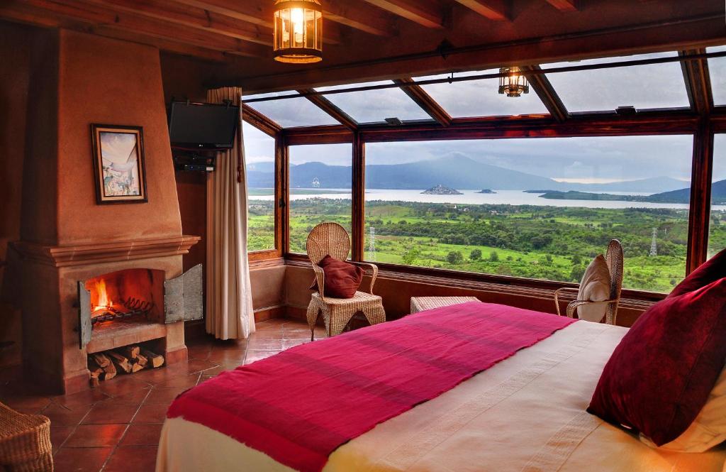 1 dormitorio con ventana grande, cama y chimenea en Porton del Cielo, en Pátzcuaro