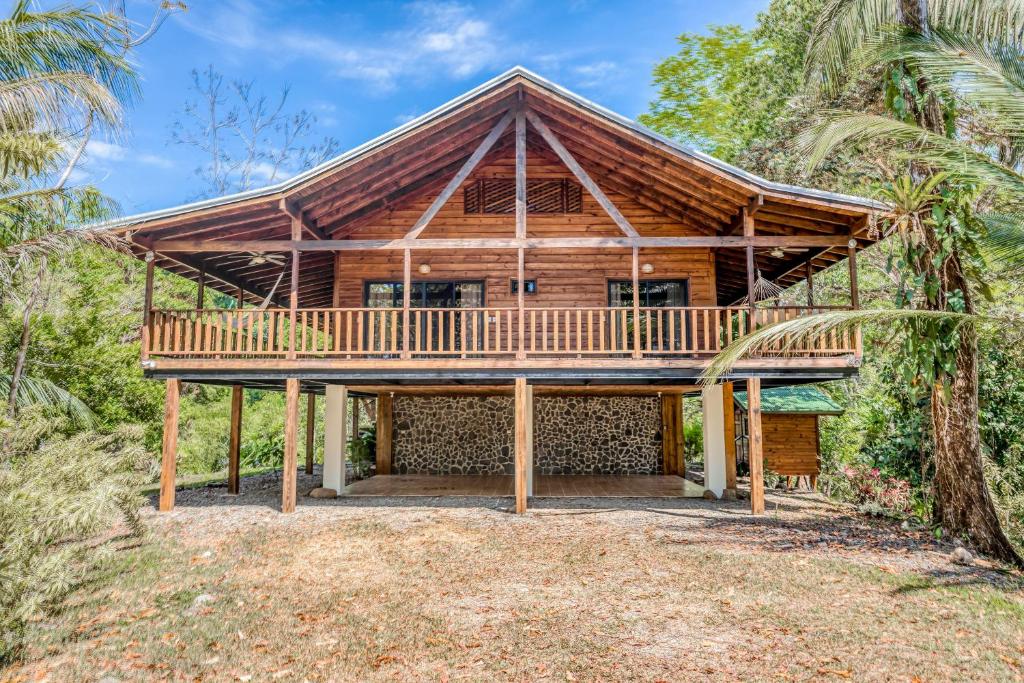 a log home with a large deck and a house at Guapil #10 in Dominical