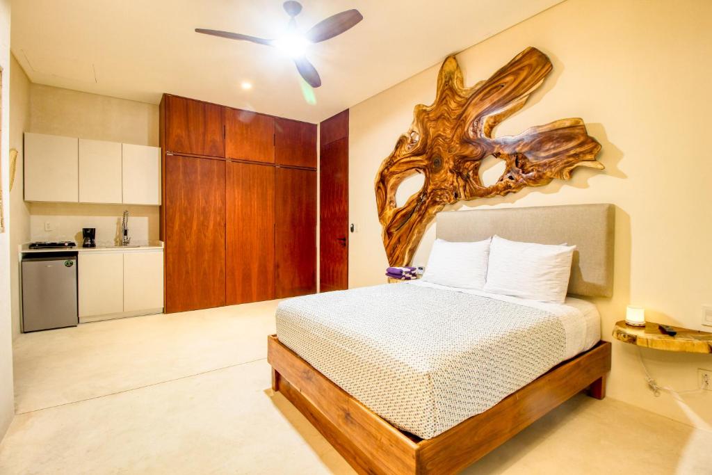 ein Schlafzimmer mit einem Bett mit einem Baumkopf an der Wand in der Unterkunft Amelia 104 Studio in Tulum