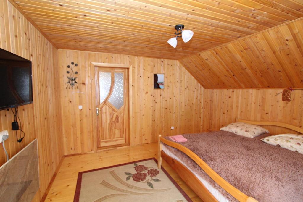 a bedroom with a bed in a wooden cabin at Багрівчанка in Yaremche