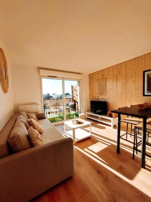 uma sala de estar com um sofá e uma mesa em Appart chaleureux proche bassin em Arès