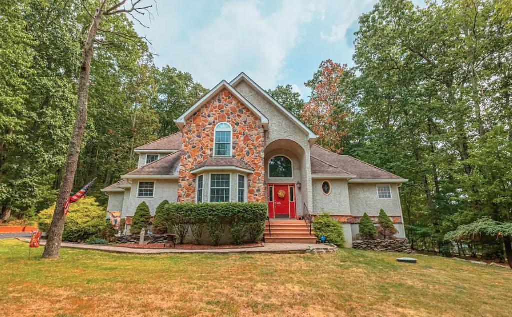 uma casa com uma porta vermelha num quintal em Blue Mountain Lake Pocono House em East Stroudsburg