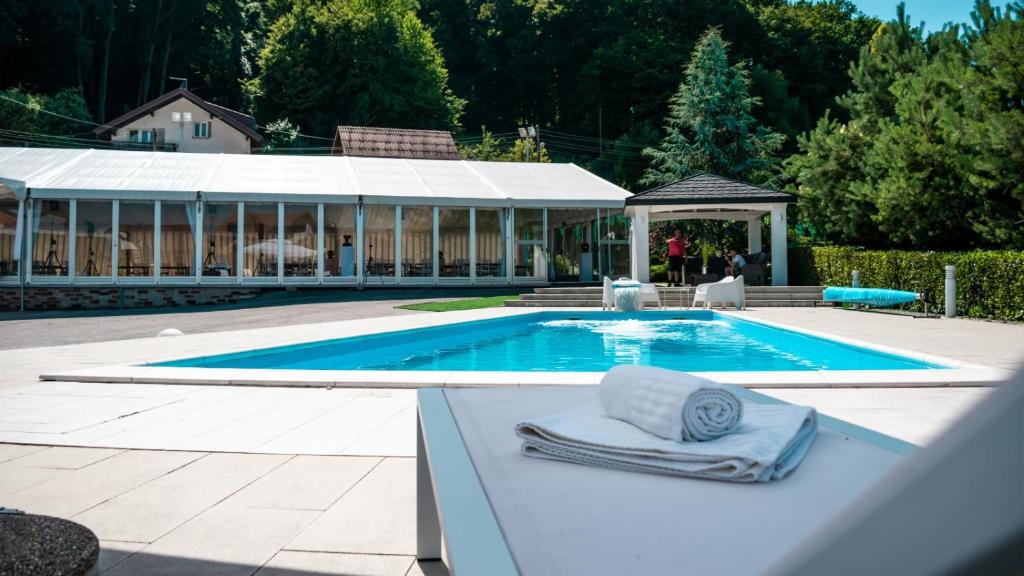 a pool with two towels on a bench next to a house at Hotel & Restaurant Se-Mi in Veliko Trgovišće