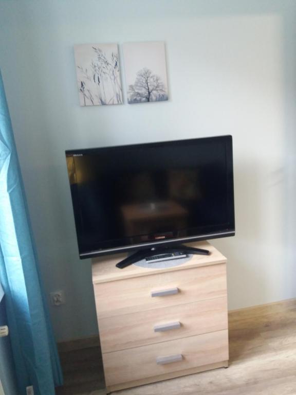a flat screen tv sitting on top of a wooden dresser at Apartament w Alei Fontann. in Szczecin