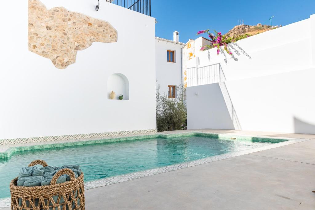 a swimming pool in front of a white building with a basket at Hostal Aljibe in Archidona