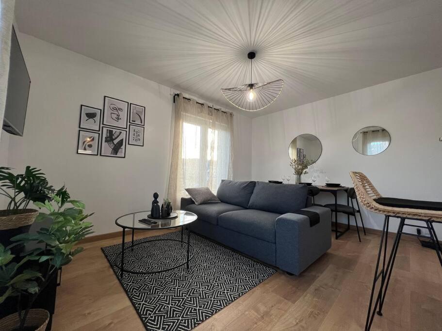 ein Wohnzimmer mit einem blauen Sofa und einem Tisch in der Unterkunft Appartement proche Disneyland in Coulommiers