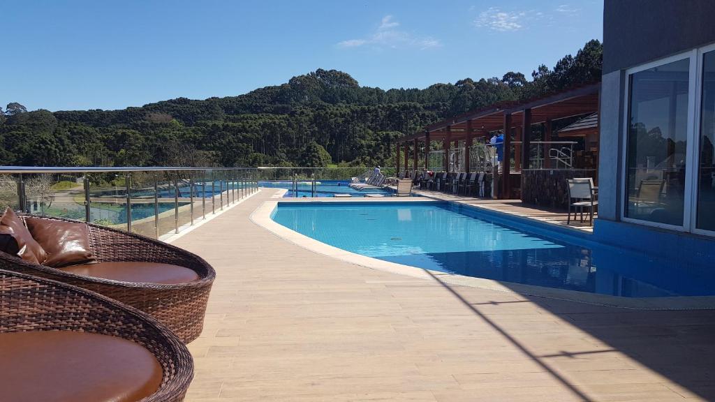a swimming pool with chairs next to a building at Golden Gramado Resort Laghetto in Gramado