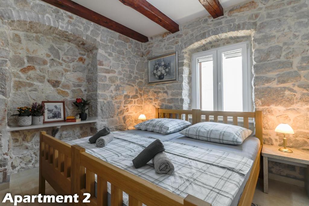Valentina Apartments Vodice في فوديس: غرفة نوم بسرير كبير في جدار حجري