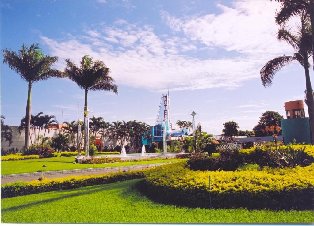 a park with palm trees and a green field at Status Motel - Check In Livre in Serra