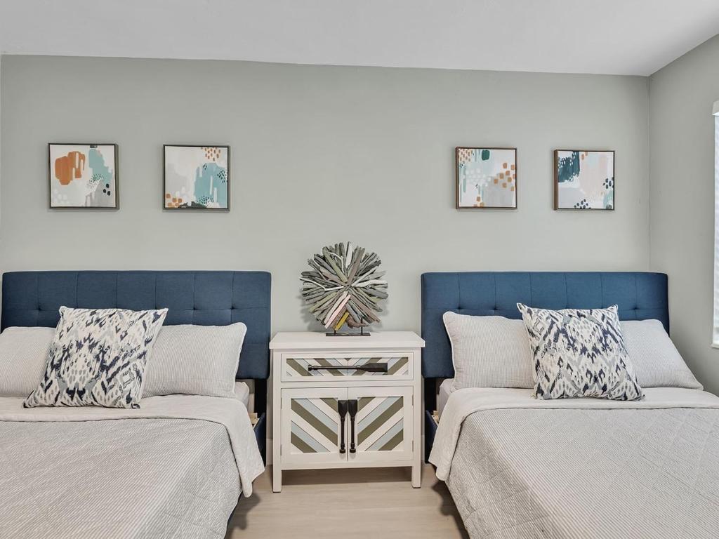 a bedroom with two beds and a nightstand between them at Dania Beach Holiday Retreat International Airport in Dania Beach