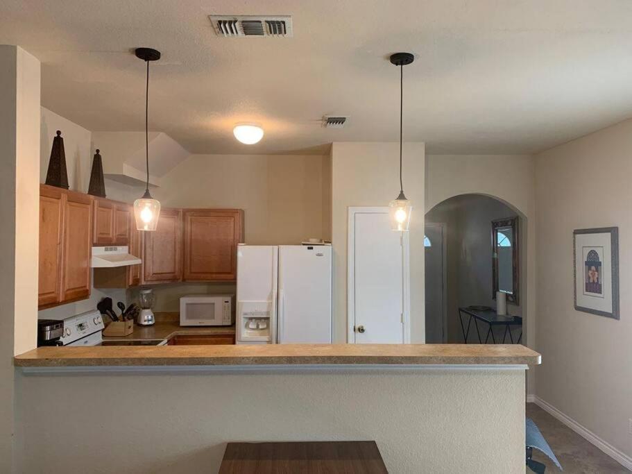 a kitchen with a white refrigerator and wooden cabinets at Camp Kingsbury- SEAWORLD and MEDICAL Center Best LOCATION in San Antonio