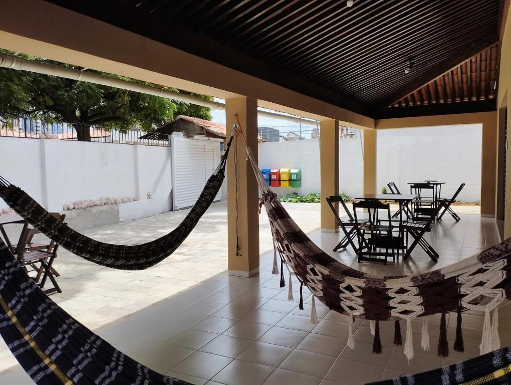 eine Terrasse mit Hängematten, einem Tisch und Stühlen in der Unterkunft A Oca Hostel Bar in João Pessoa