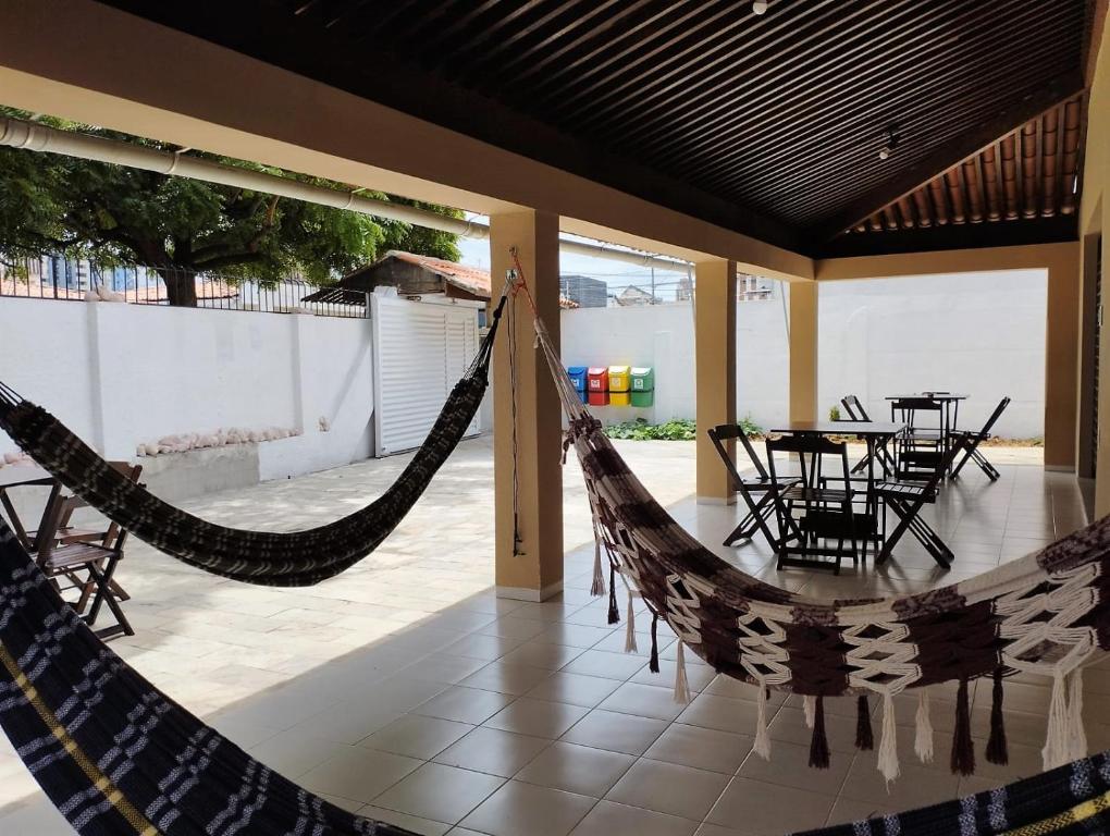 a patio with hammocks and a table and chairs at A Oca Hostel Bar in João Pessoa