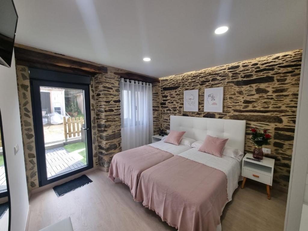 een slaapkamer met een bed en een bakstenen muur bij A CASIÑA DE ISABEL in Arzúa