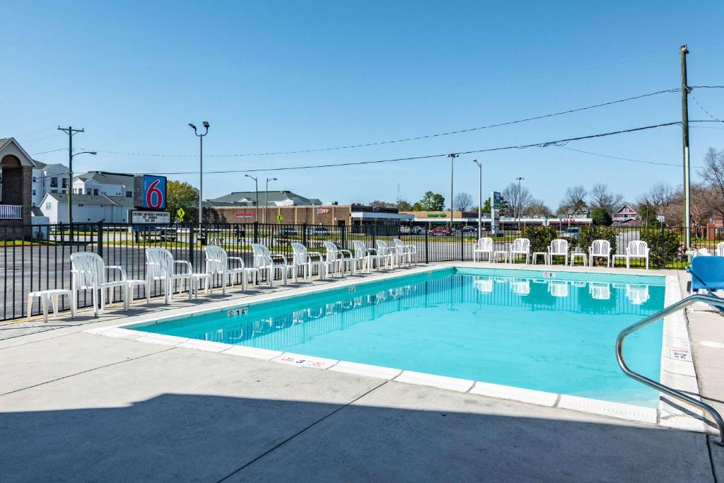 a swimming pool with white chairs and a fence at Motel 6-Portsmouth, VA in Portsmouth