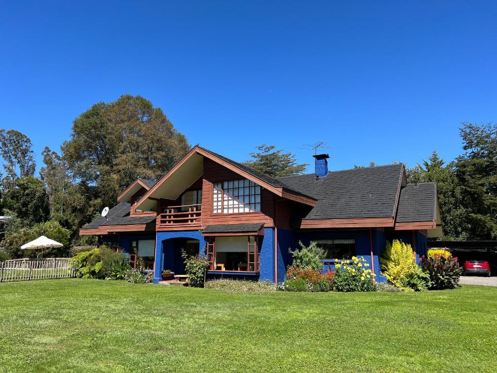 a house with a gambrel roof on a lawn at Agua y Campo Hotel Boutique in Osorno