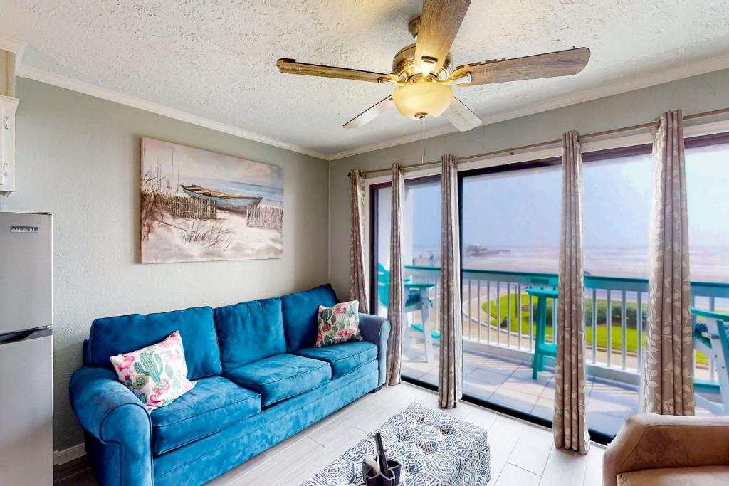 a living room with a blue couch and a balcony at Sun of a Beach in Galveston