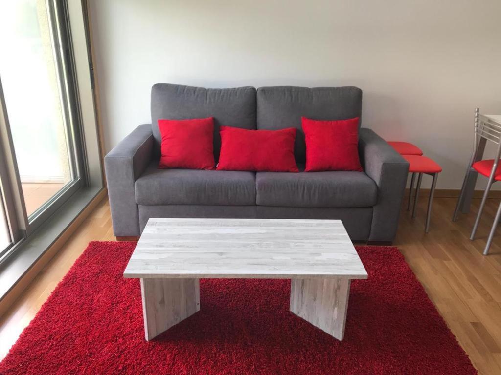 sala de estar con sofá y almohadas rojas en APARTAMENTO PLAYA A XUNQUEIRA, en Moaña